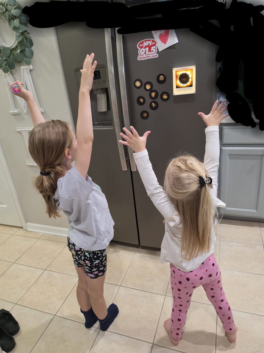 Two children reaching up to tap a disc on the Waxlane player on their family fridge.